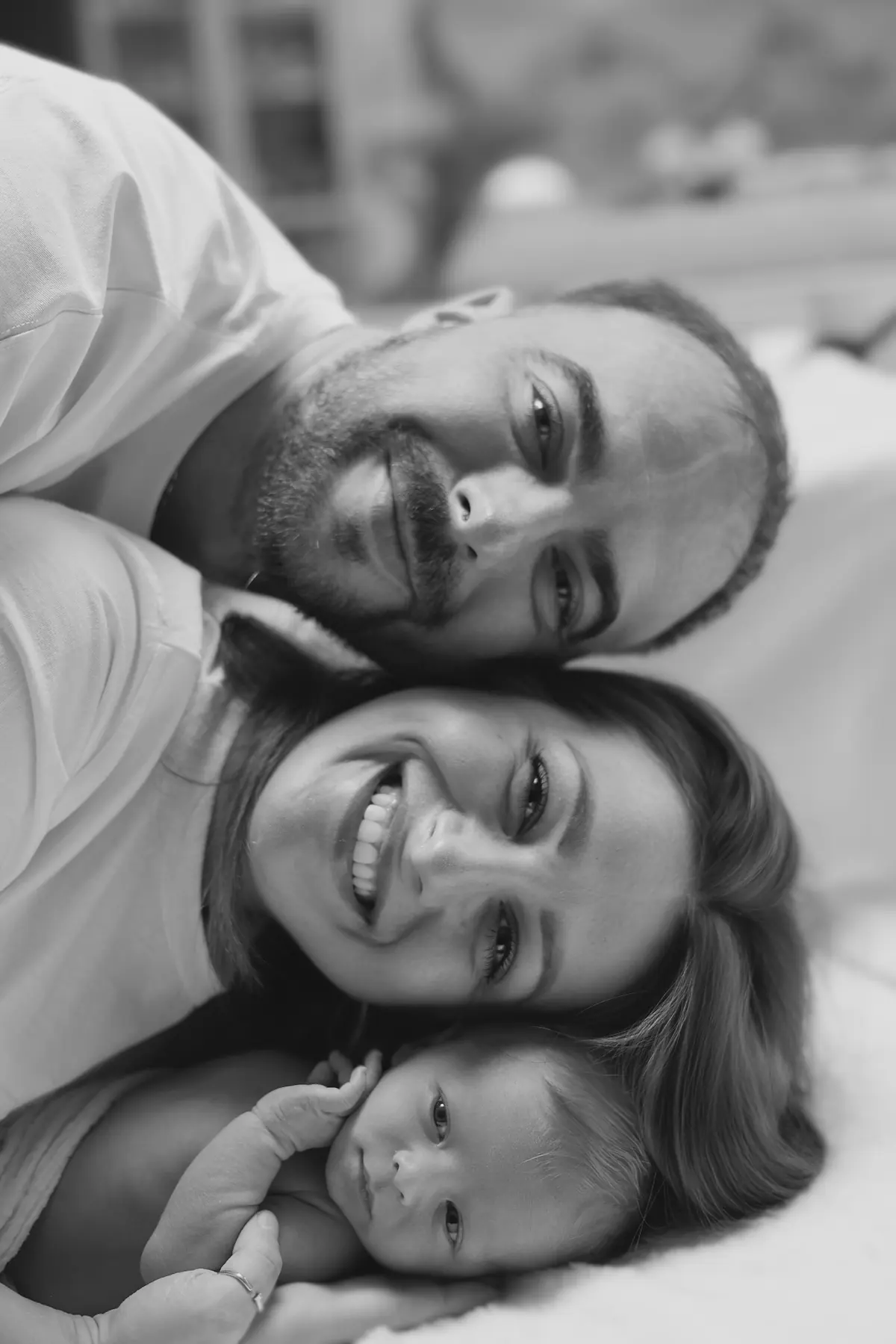 Black-and-white family portrait with mother, father, and newborn